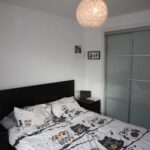 Cox & Co Estate agent in Edinburgh, Scotland. A bedroom at Salamander Court boasts a double bed with charming owl-themed bedding. A round, white paper lamp hangs from the ceiling. The nightstand on the left holds a few items, while on the right stands a large sliding door wardrobe with a frosted glass finish.