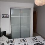 Cox & Co Estate agent in Edinburgh, Scotland. A bedroom on Salamander Court features a bed with owl-patterned bedding. A mirrored sliding closet door is centered in the image, reflecting part of the room. Above the bed, there's wall art and the letters "DAD" framed on the wall. A spherical light fixture hangs from the ceiling.