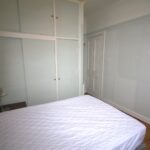 Cox & Co Estate agent in Edinburgh, Scotland. A small bedroom with a white quilted bed, a bedside table with a lamp, and built-in white wardrobes with glass panels. The grey walls with white trim beautifully contrast the wooden floor, and there's a closed door in the background. Perfect for anyone working with an estate agent in Edinburgh.